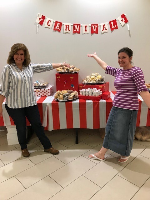 two women showcasing a carnival table full of food